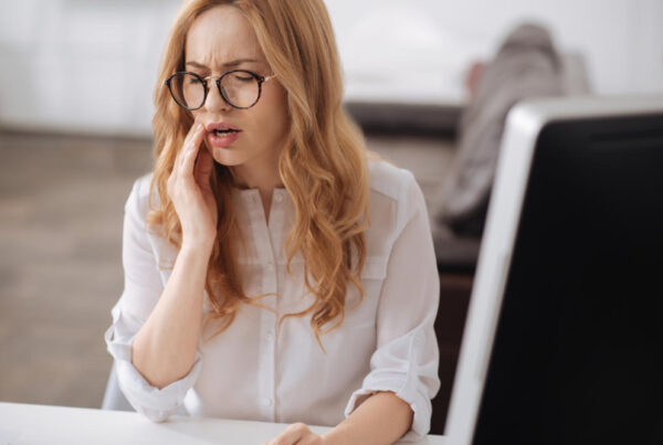 Woman experiencing dental pain, representing common symptoms of tooth sensitivity – Smile Dental Partners
